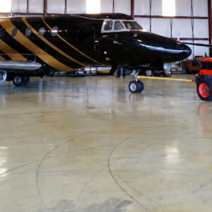 Tornillo suelto en el suelo de un hangar frente a una aeronave y un tractor de remolque