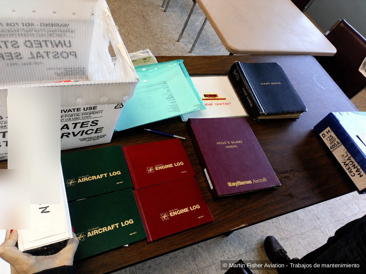 Libros de registro y manuales de una aeronave sobre la mesa durante una revisión documental