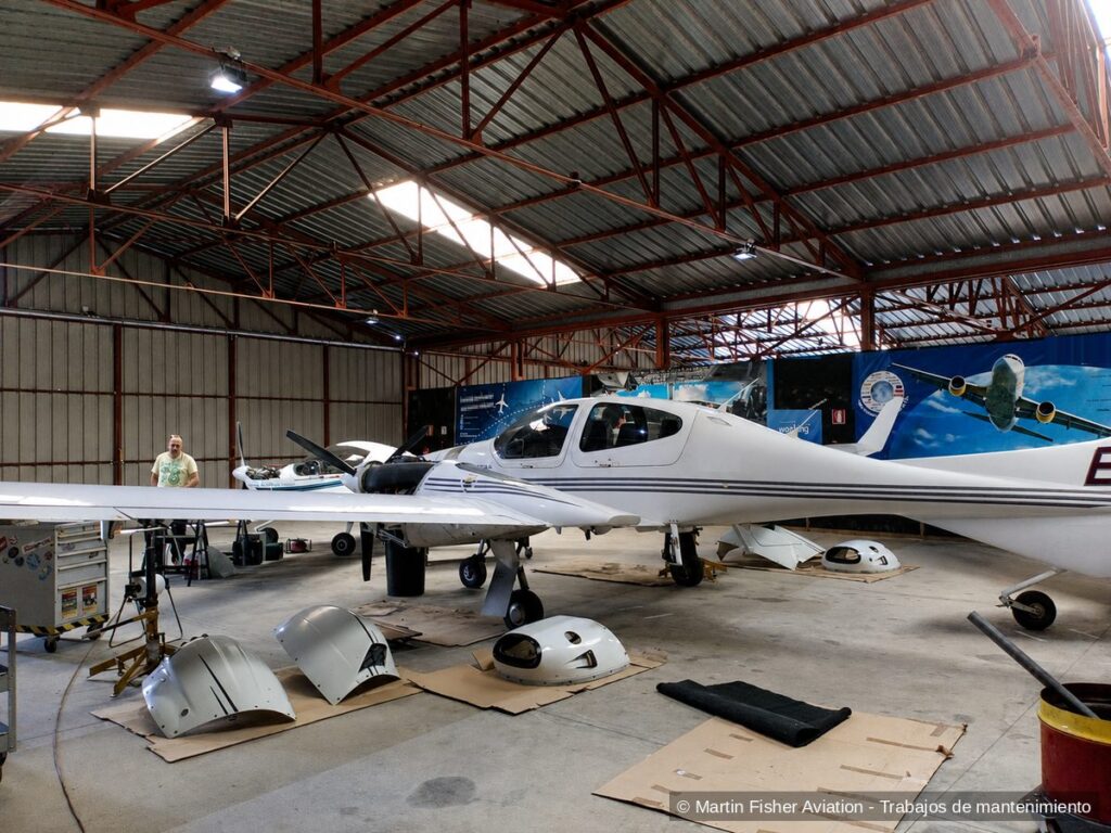 Técnico de mantenimiento trabajando en un hangar con dos aeronaves desmontadas